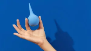 Une main tenant une poire à lavement bleue