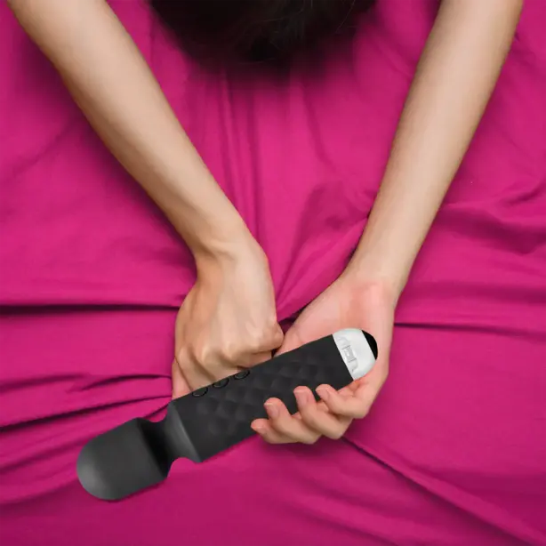 vibromasseur clitoridien tenu dans les mains d'une femme